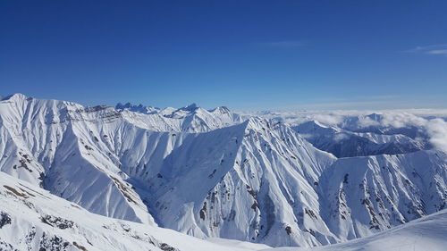 Panoramic view of snowcapped mountains against blue sky