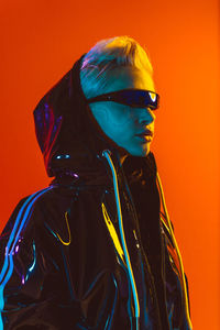 Young woman wearing sunglasses while standing against yellow background