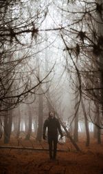 Full length of man standing in forest during foggy weather