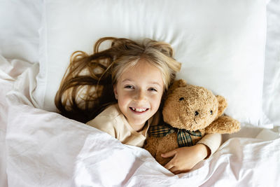 Portrait of young woman with teddy bear on bed