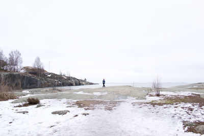 Man standing on frozen landscape against clear sky