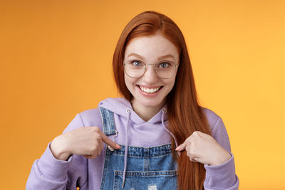 Portrait of a smiling young woman against yellow background