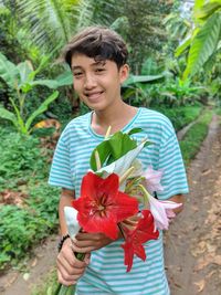 Portrait of smiling teenage boy holding flowers