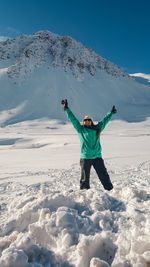 Full length of woman walking on snowcapped mountain against sky