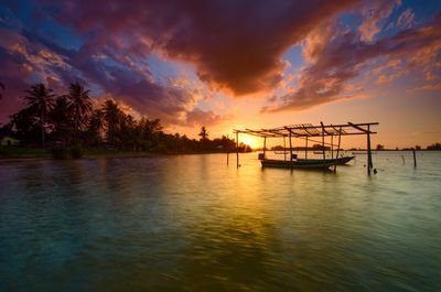 Silhouette of fishing boat in sea against sky during sunset