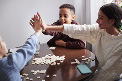 Girl and boys playing scrabble at dining table