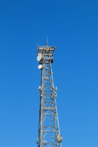 Low angle view of communications tower against clear blue sky