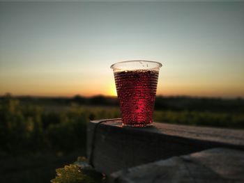 Close-up of beer glass against orange sky