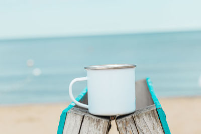 Glass of water on beach against sky