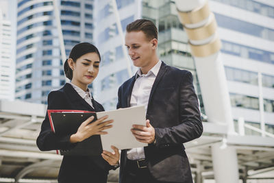 Low angle view of business people discussing while standing against building