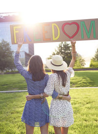 Rear view of women standing with text