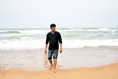 Full length of man walking at beach against sky