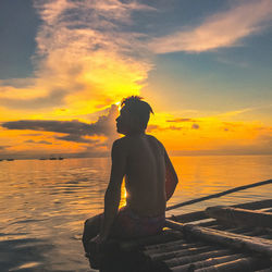 Silhouette man looking at sea against sky during sunset