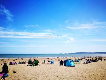 Group of people on beach against blue sky