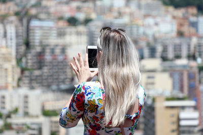 Woman photographing with mobile phone in city