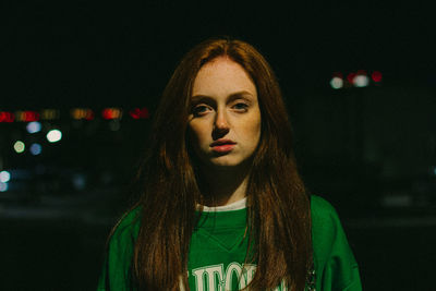 Portrait of young woman against black background