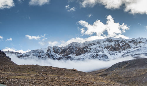 Scenic view of snowcapped mountains against cloudy sky