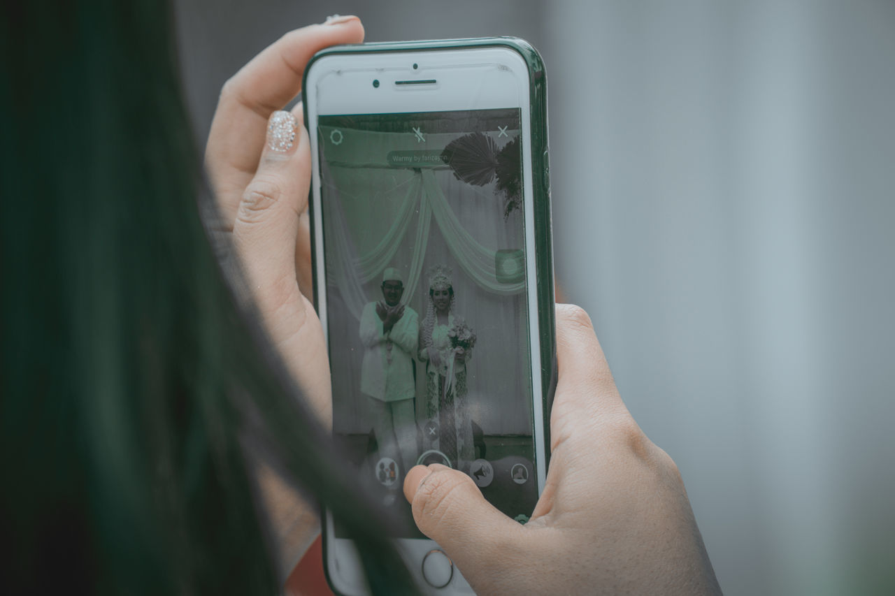 MIDSECTION OF MAN USING MOBILE PHONE IN MIRROR