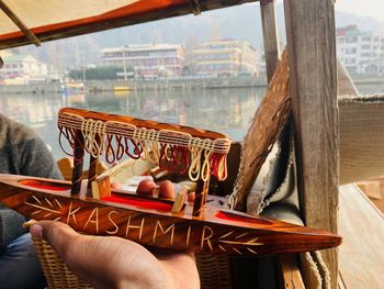 Hands of a person holding boat against river