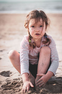 Happy girl sitting on sand at beach