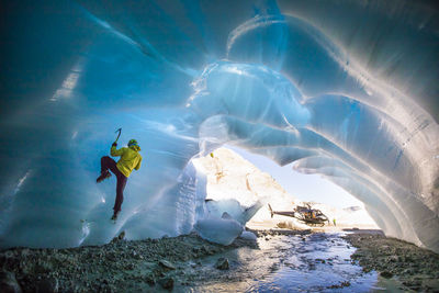 Man ice climbing in ice cave during luxury adventure tour.