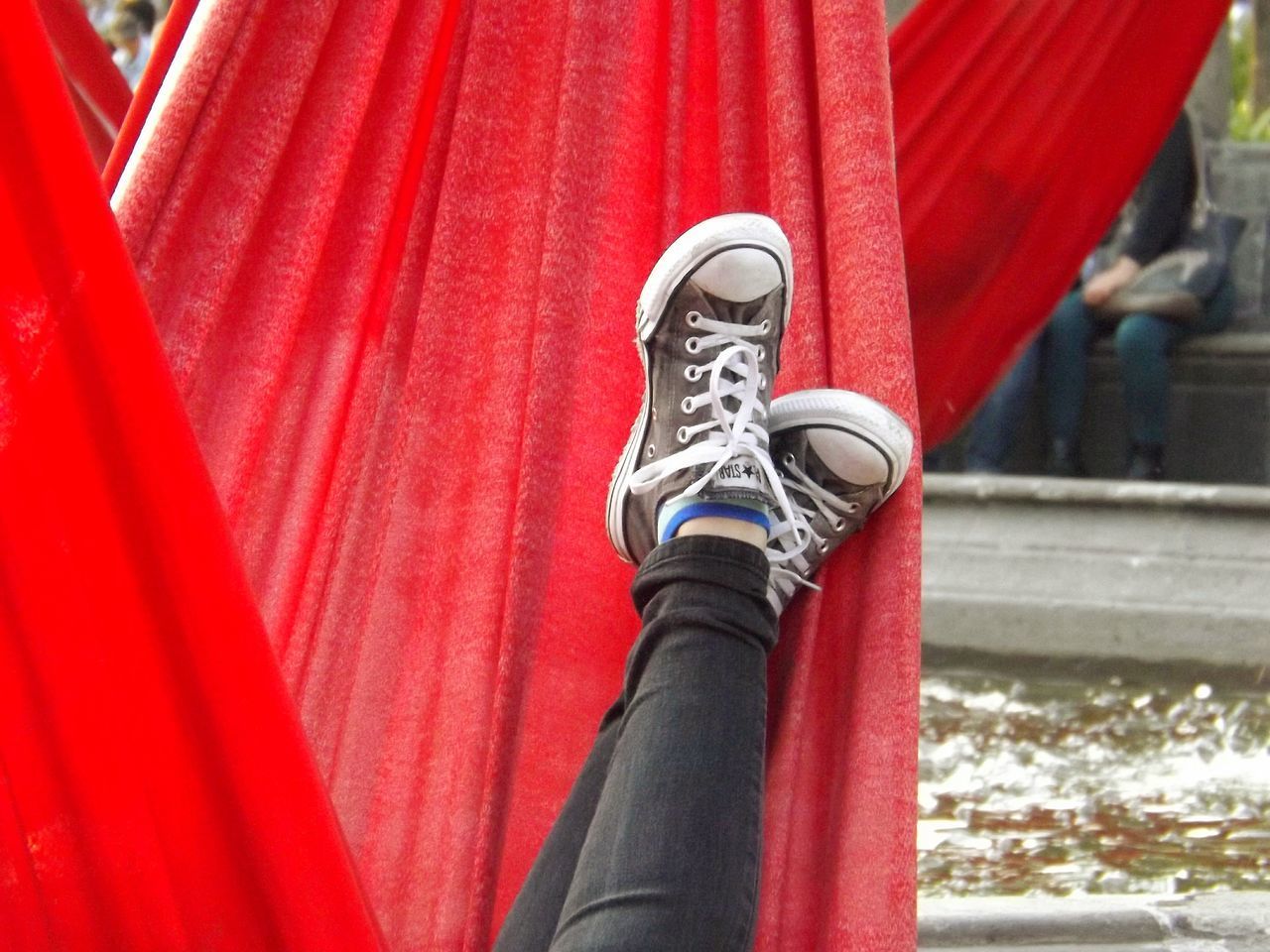 LOW SECTION OF PERSON STANDING ON RED METAL OUTDOORS