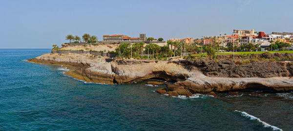 Rocks on beach by sea against clear sky