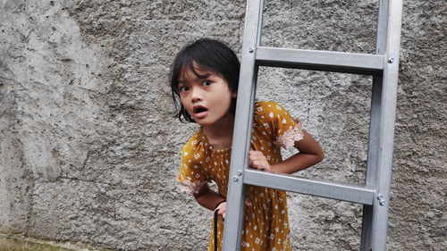 Portrait of young woman standing against wall