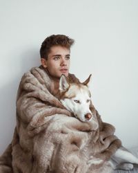 Portrait of young man sitting against white background