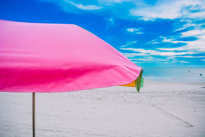 Pink umbrella on beach against sky