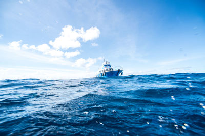 Boat sailing in sea against blue sky