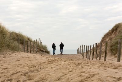 People on beach against cloudy sky