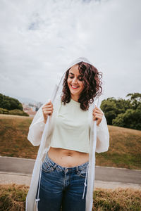 Portrait of a smiling young woman standing against sky