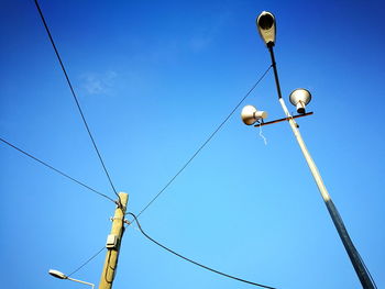 Low angle view of telephone pole against blue sky