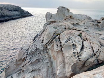 Rock formation on beach against sky