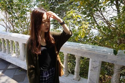 Full length of woman standing by railing against trees