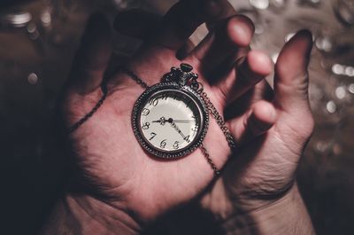 Close-up of cropped hand holding clock