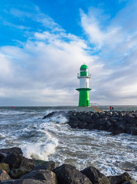 Lighthouse by sea against sky