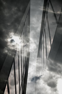 Low angle view of suspension bridge against cloudy sky