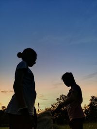 Rear view of couple standing against sky during sunset