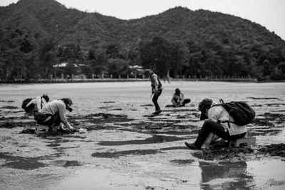 Rear view of people on lake against trees