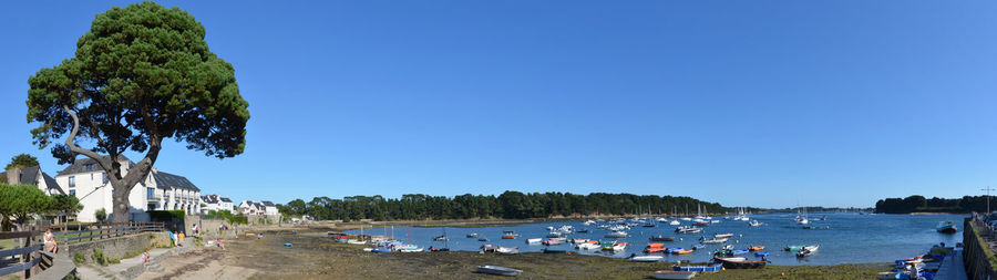 Panoramic view of people on sea against clear blue sky