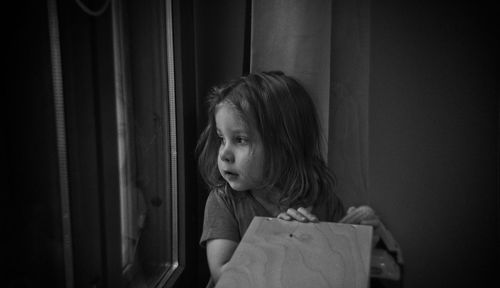 Girl looking through window at home