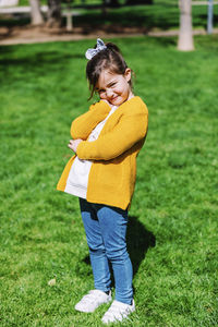 Portrait of cute smiling girl standing on grassy field in park