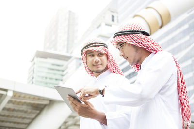 Low angle view of man holding mobile phone standing in city