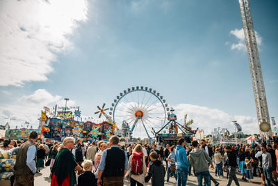 People at amusement park against sky