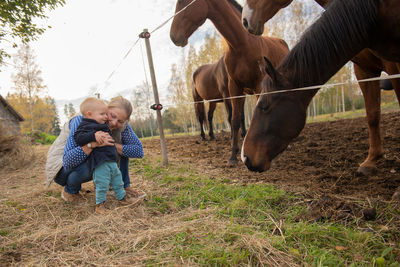 Mother and son playing with horses in ranch