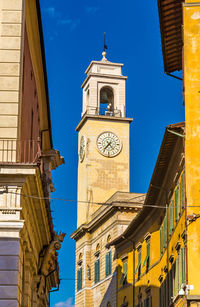 Low angle view of clock tower amidst buildings against sky