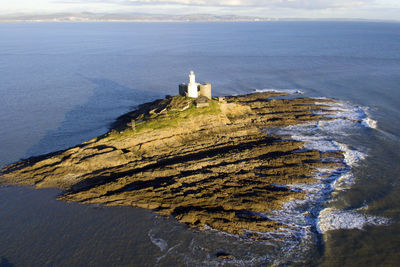 High angle view of lighthouse amidst sea and buildings