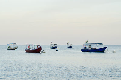 Boats sailing in sea against clear sky